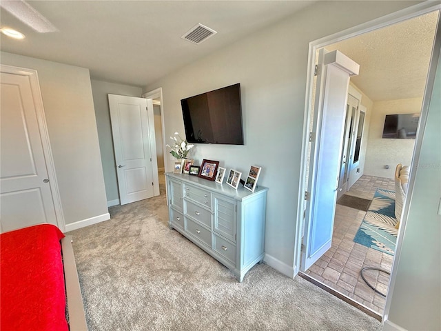 bedroom with baseboards, visible vents, and light carpet