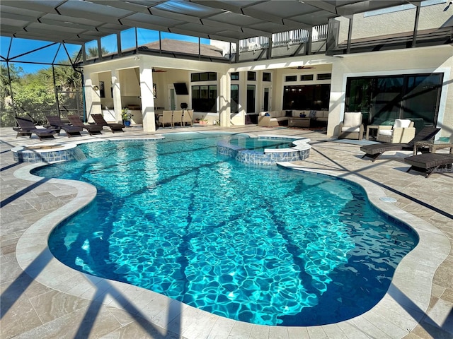 view of pool with a pool with connected hot tub, a lanai, an outdoor hangout area, ceiling fan, and a patio area