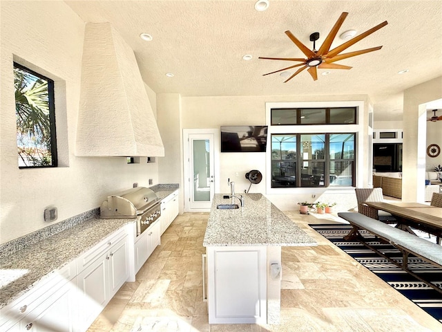 kitchen with white cabinetry, a textured ceiling, ceiling fan, and a sink