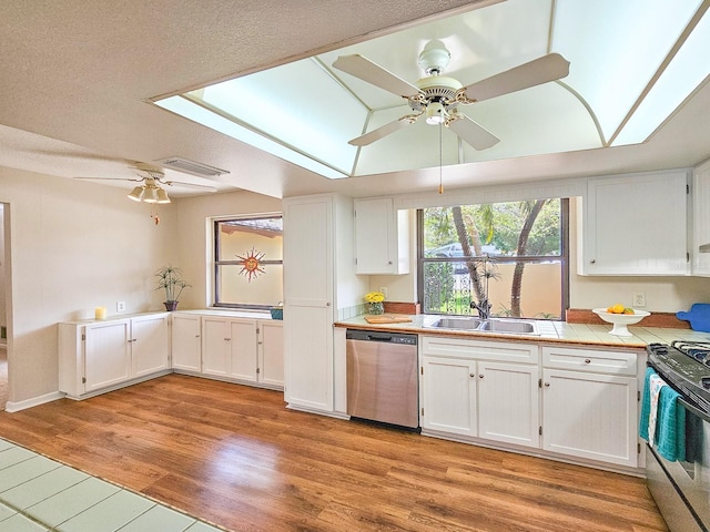 83 Farragut Dr, Palm Coast, FL 32137 - kitchen with stainless steel appliances, ceiling fan, tile counters, white cabinets, and light wood-type flooring