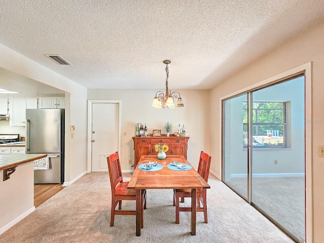 83 Farragut Dr, Palm Coast, FL 32137 - dining area featuring light carpet, a chandelier, and a textured ceiling