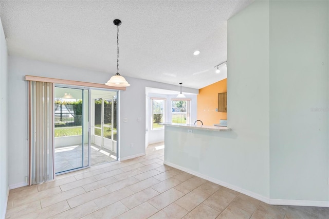 unfurnished dining area with baseboards, a textured ceiling, and rail lighting