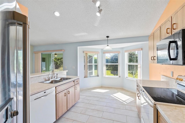 kitchen featuring white dishwasher, a sink, electric range oven, black microwave, and stainless steel fridge