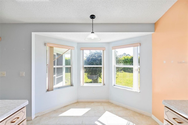 unfurnished dining area with light tile patterned floors, baseboards, and a textured ceiling