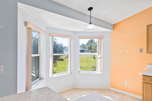 unfurnished dining area featuring light tile patterned flooring, baseboards, and a textured ceiling