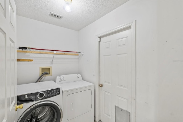 laundry area featuring visible vents, a textured ceiling, washing machine and dryer, and laundry area