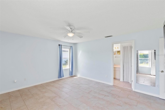 spare room featuring a ceiling fan, visible vents, and baseboards