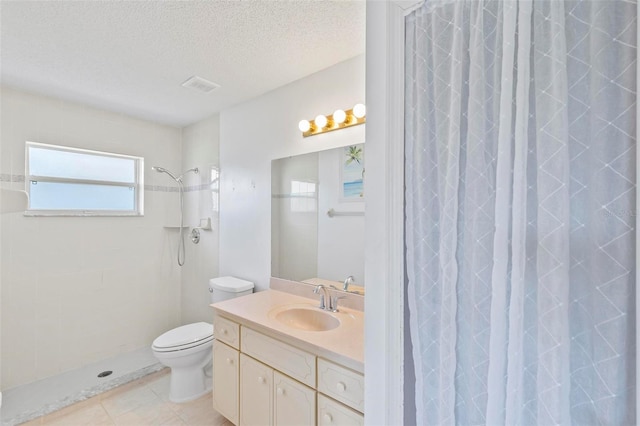 bathroom with vanity, tiled shower, tile patterned flooring, a textured ceiling, and toilet