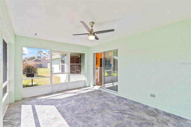 unfurnished sunroom featuring ceiling fan