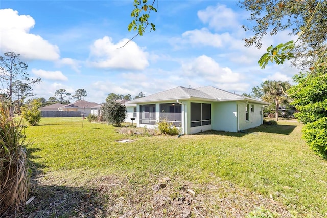 back of property with a lawn and a sunroom