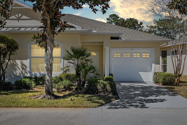 view of front of house featuring a garage, roof with shingles, driveway, and stucco siding