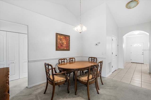 dining room with light carpet, visible vents, arched walkways, and lofted ceiling