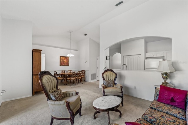 living room with arched walkways, visible vents, and light colored carpet