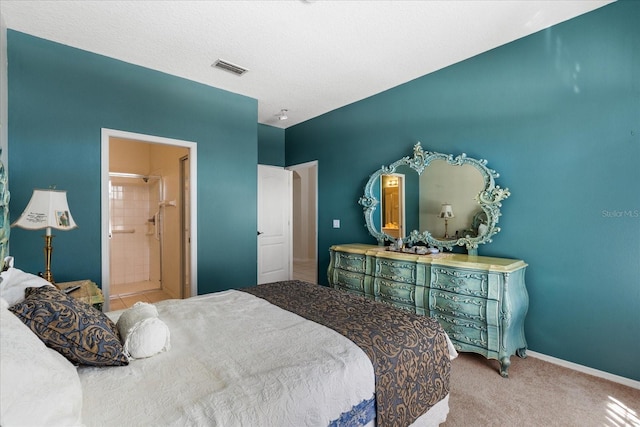 carpeted bedroom with visible vents, ensuite bath, and baseboards