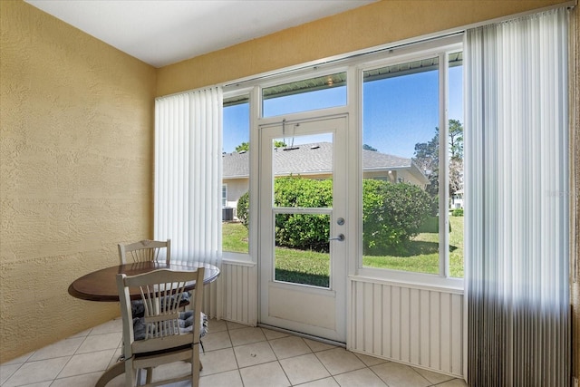 entryway with a wealth of natural light, light tile patterned floors, and a textured wall