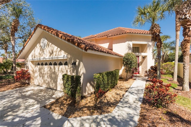 mediterranean / spanish home with stucco siding, a tiled roof, concrete driveway, and a garage