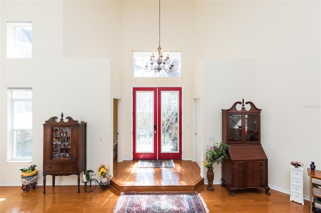 foyer entrance featuring a chandelier, baseboards, a high ceiling, and wood finished floors