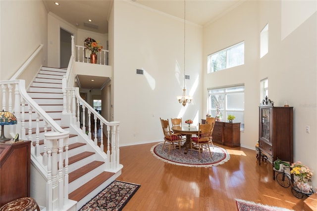 interior space with baseboards, a notable chandelier, wood finished floors, and ornamental molding