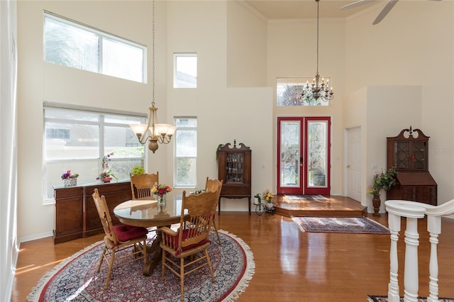 dining room featuring wood finished floors, a high ceiling, ornamental molding, french doors, and a chandelier