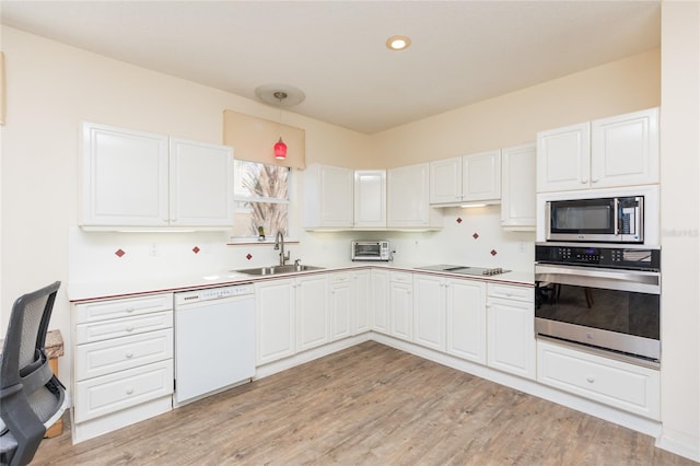 kitchen with a sink, stainless steel appliances, light wood-style floors, and white cabinetry