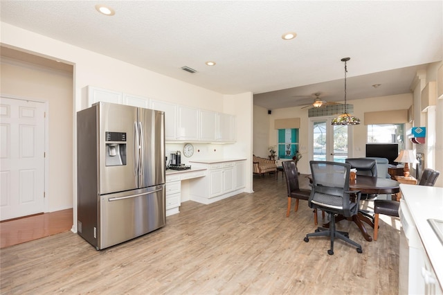 kitchen featuring light wood finished floors, stainless steel fridge, and white cabinets