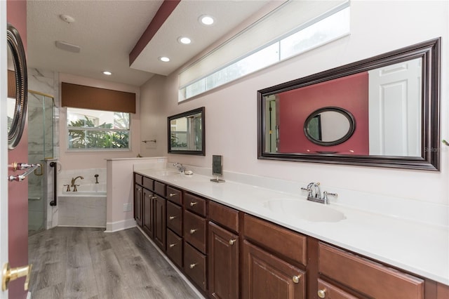 full bath featuring a bath, wood finished floors, a stall shower, and a sink