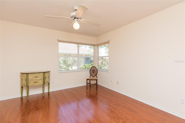 unfurnished room featuring ceiling fan, baseboards, a textured ceiling, and wood finished floors