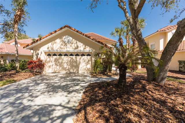 mediterranean / spanish home with stucco siding, concrete driveway, an attached garage, and a tile roof