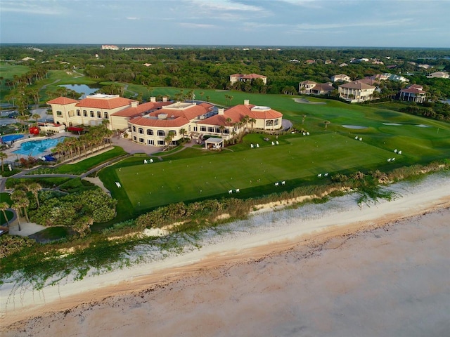 drone / aerial view with a water view, view of golf course, and a wooded view