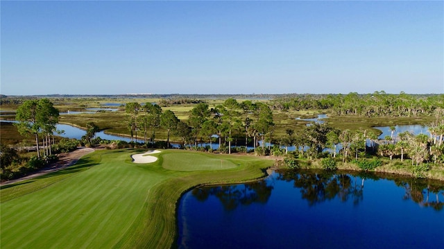 view of property's community with golf course view, a yard, and a water view