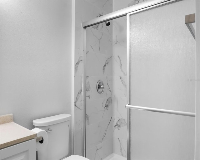 bathroom featuring a marble finish shower, toilet, and vanity