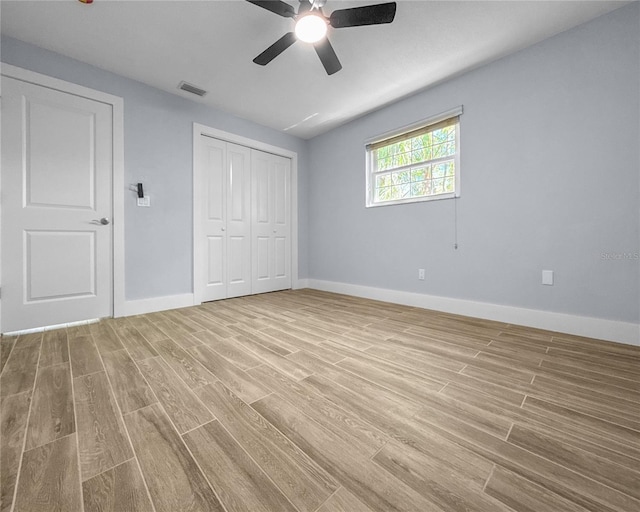 unfurnished bedroom featuring a ceiling fan, baseboards, visible vents, light wood-style flooring, and a closet