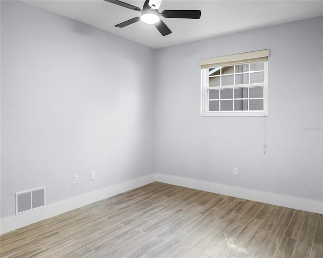 spare room with ceiling fan, visible vents, baseboards, and wood finished floors