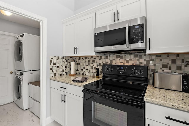 kitchen featuring black electric range, stacked washer and dryer, white cabinets, stainless steel microwave, and marble finish floor