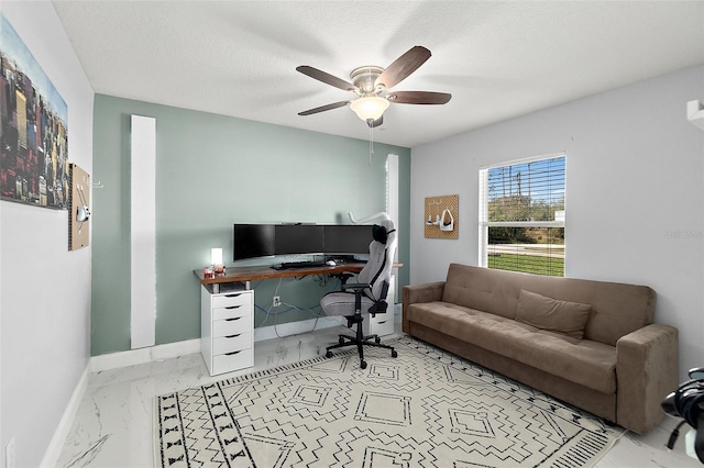 home office featuring marble finish floor, a textured ceiling, a ceiling fan, and baseboards