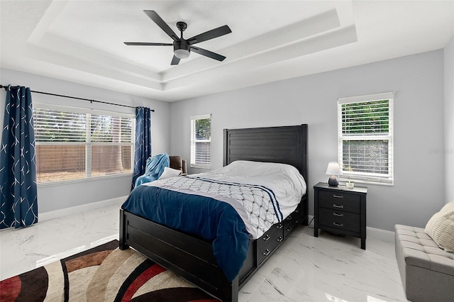 bedroom with marble finish floor, a raised ceiling, and baseboards