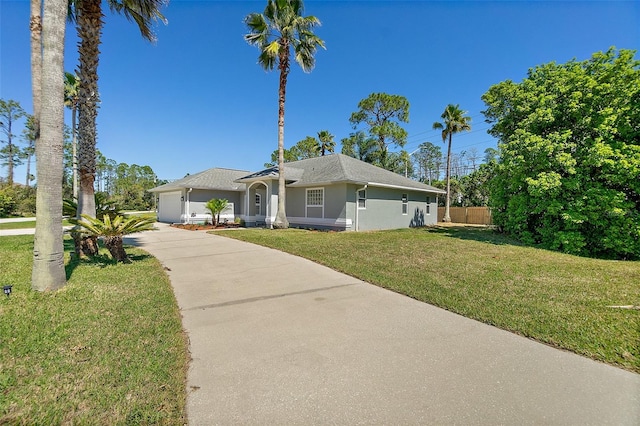 ranch-style house featuring an attached garage, a front lawn, fence, stucco siding, and driveway