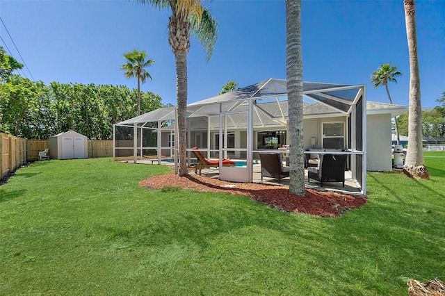 back of house with an outbuilding, a fenced backyard, a shed, glass enclosure, and a patio area