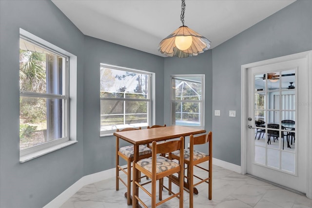 dining space featuring plenty of natural light, baseboards, and marble finish floor