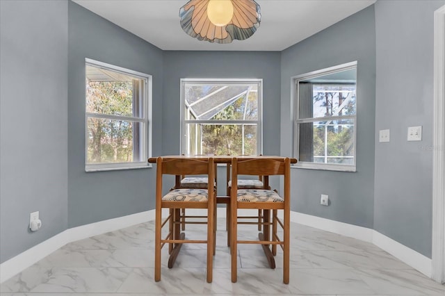 dining space with marble finish floor and baseboards