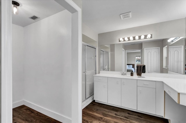 full bathroom with vanity, wood finished floors, visible vents, baseboards, and a shower stall