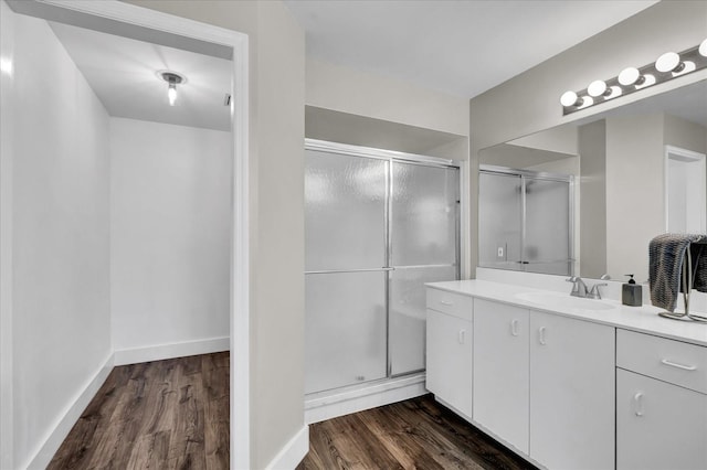 bathroom with vanity, a shower stall, wood finished floors, and baseboards