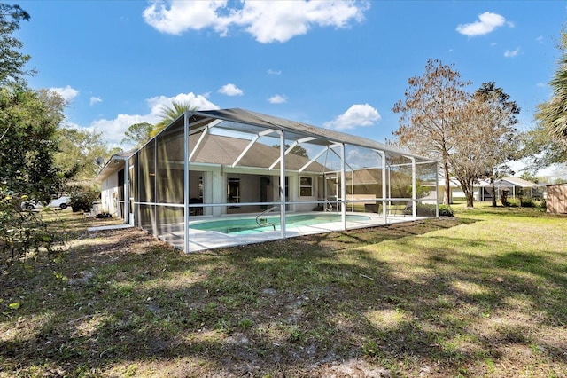 rear view of property featuring an outdoor pool, a yard, a patio, and a lanai