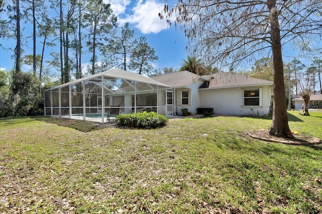 back of property with glass enclosure, a yard, an outdoor pool, and stucco siding