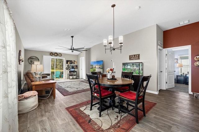 dining area with visible vents, baseboards, lofted ceiling, ceiling fan with notable chandelier, and wood finished floors