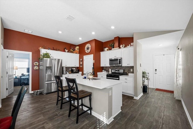 kitchen featuring visible vents, a sink, vaulted ceiling, appliances with stainless steel finishes, and a kitchen island with sink