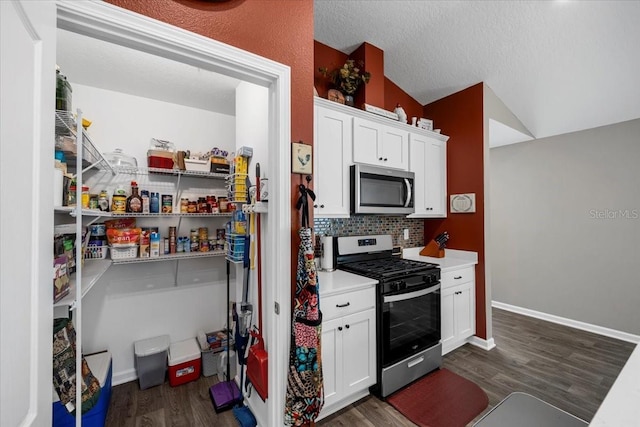 kitchen featuring tasteful backsplash, dark wood finished floors, light countertops, white cabinets, and stainless steel appliances