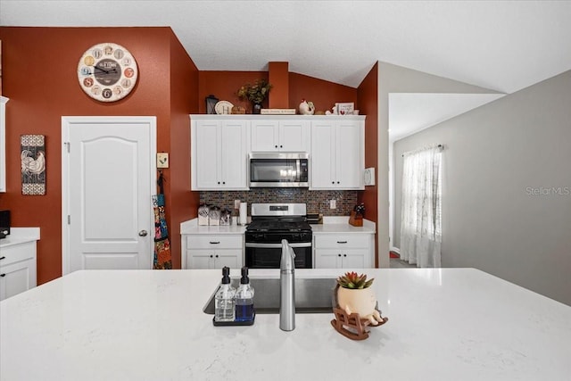 kitchen featuring white cabinetry, lofted ceiling, light countertops, and appliances with stainless steel finishes