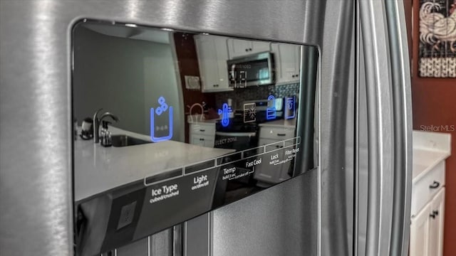 kitchen with a sink, appliances with stainless steel finishes, light countertops, and white cabinetry