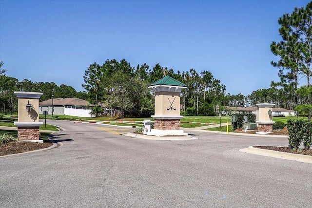 view of road with a gated entry, curbs, and traffic signs